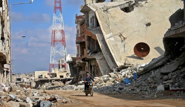 A Syrian man riding his motorcycle past damaged buildings in the southern city of Daraa, March 16, 2017.